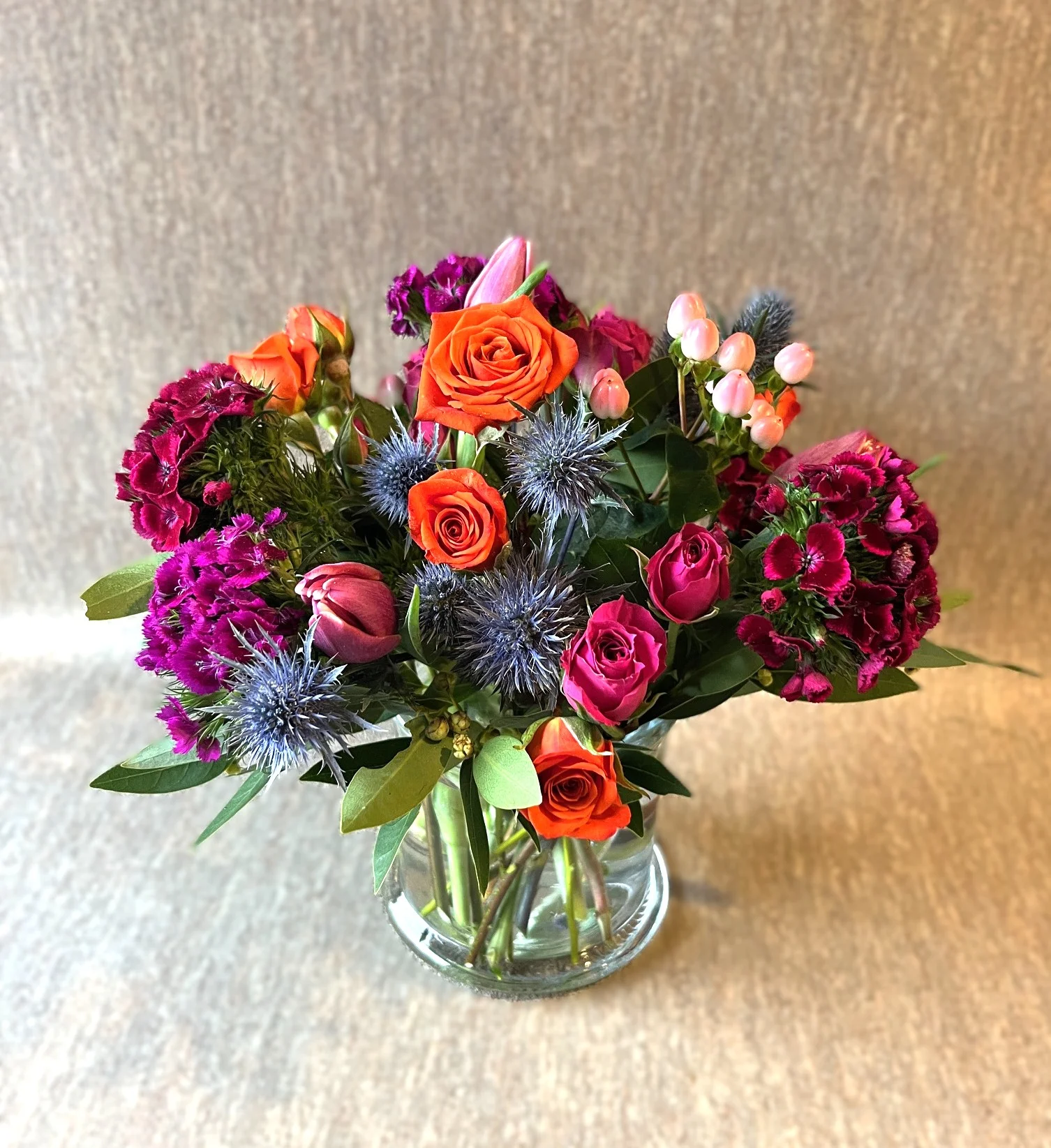 Textural floral bouquet with fun thistle, roses, bay, and sweet William, a nice mix of rich bold colors