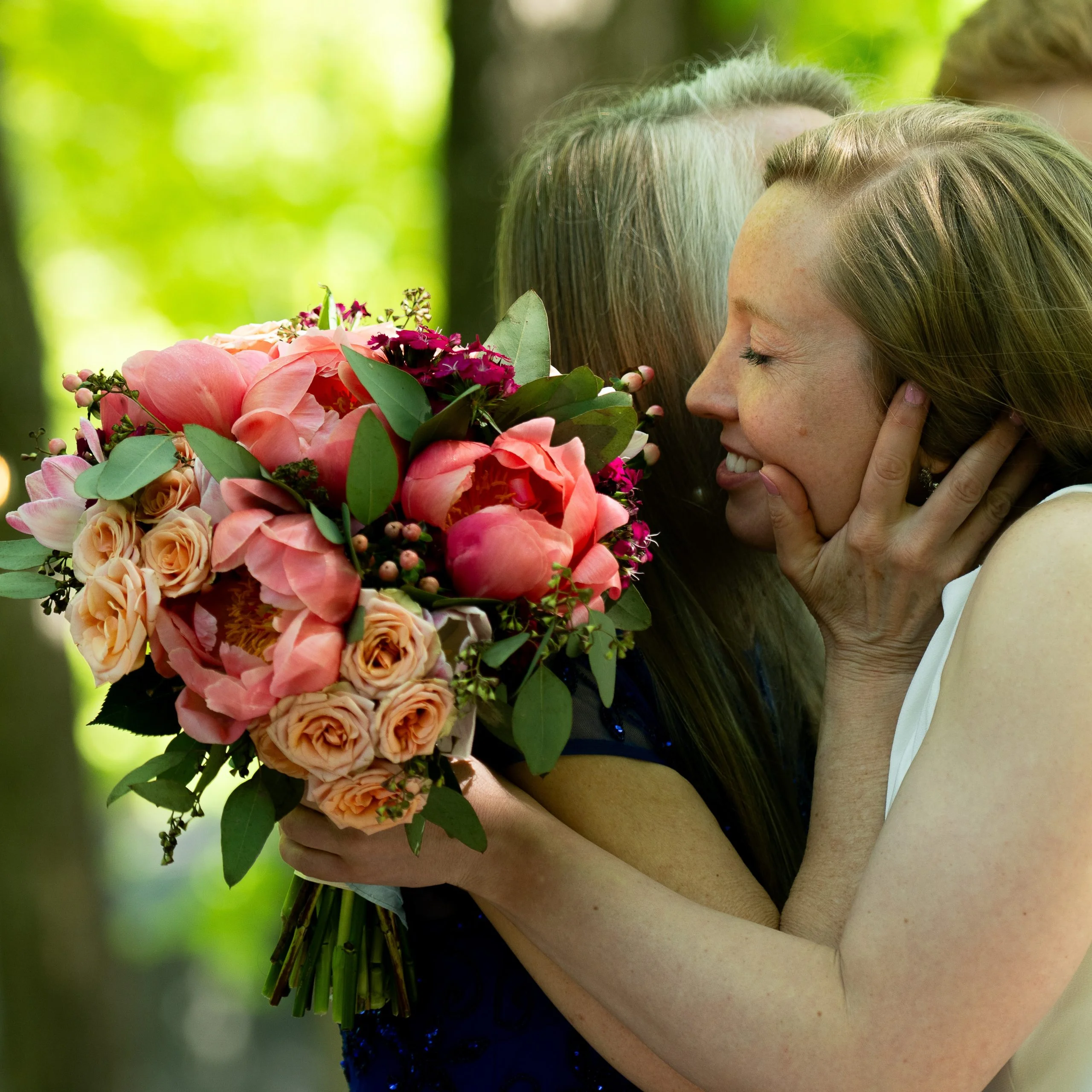 Bride hugging on her wedding day white holding a bouquet of spring flowers in warmer colors.